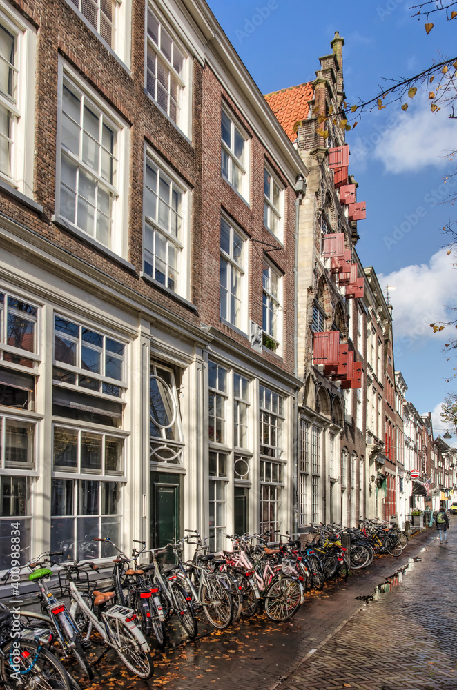Delft, The Netherlands, November 11, 2020: many parkd bicycles in front of traditional facades along Koornmarkt canal in the old town