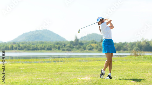 Golfer sport course golf ball fairway. People lifestyle woman playing game golf and hitting go on green grass river and mountain background. Asia female player game shot in summer. 