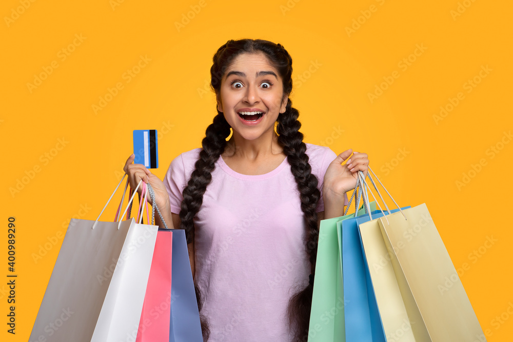Excited indian woman holding plastic credit card and shopping bags Excited indian woman holding plastic credit card and shopping bags