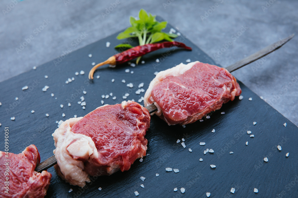 Raw and fresh beef meat steaks on the black background.