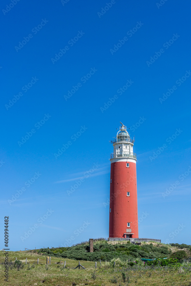 The bright red lighthouse of the Dutch island of Texel against an intense blue sky