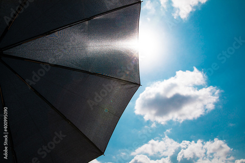 Black umbrella open for protect sunshine, high uv sun on blue sky with cloud	