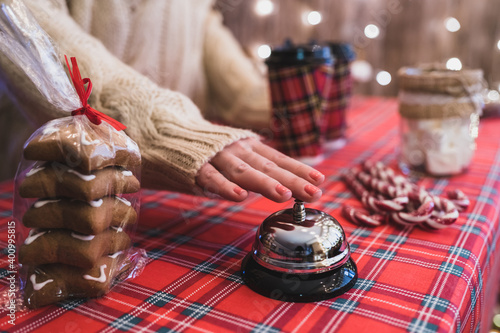 Christmas pastry shop. Woman seller, waitress ringing bell to warn that hot chocolate in paper cup is ready. Gingerbread cookies, marshmallows in a small cozy cafe.