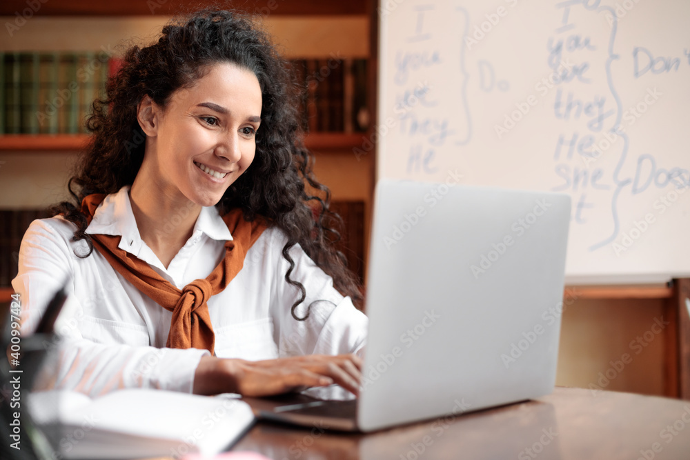 Young woman sitting at desk, using computer and typing Young woman sitting at desk, using computer and typing