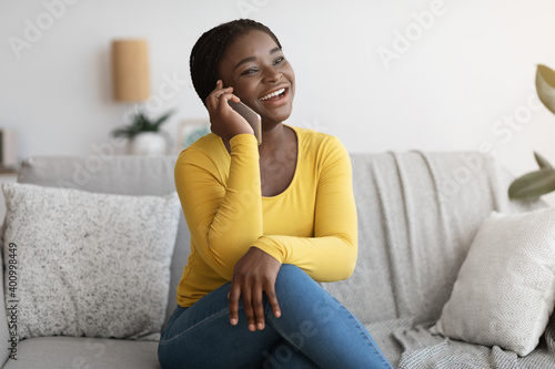 Positive African American Lady Talking On Mobile Phone At Home, Enjoying Conversation