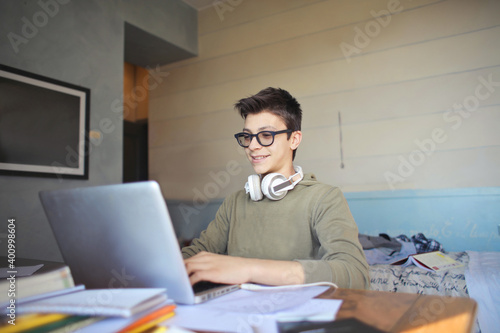 young boy uses his laptop in his bedroom