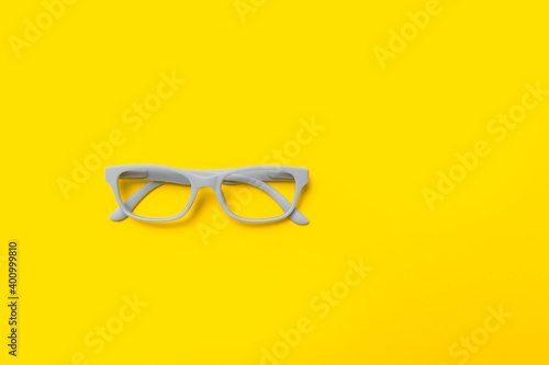 Grey glasses on a yellow background. Top view, space for your text.