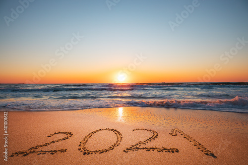 Happy New Year 2021 concept, lettering on the beach. Written text on the sea beach at sunrise.