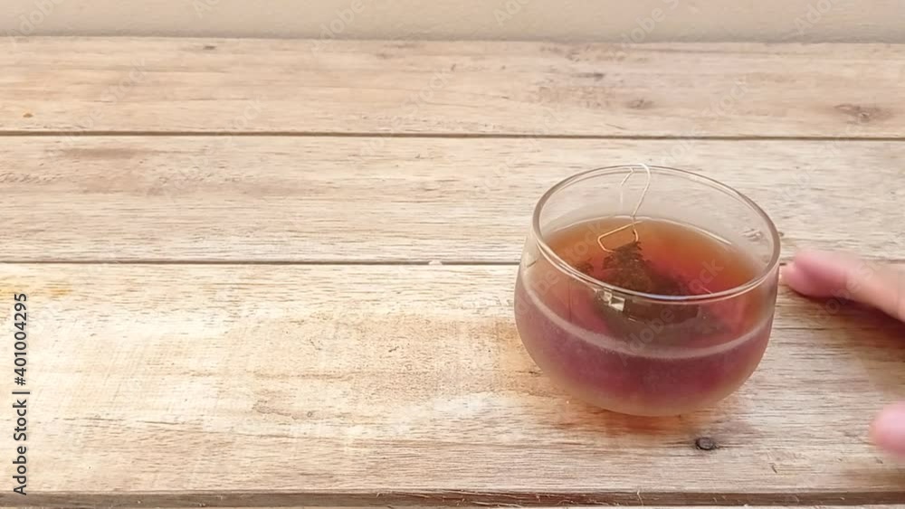 holding a glass of tea with a tea bag on it holding a glass of tea with a tea bag on it