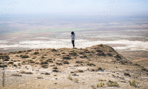 Female person stands on the hill with majestic background landscape and checks her phone photo