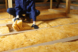 Man installing thermal insulation layer under the roof