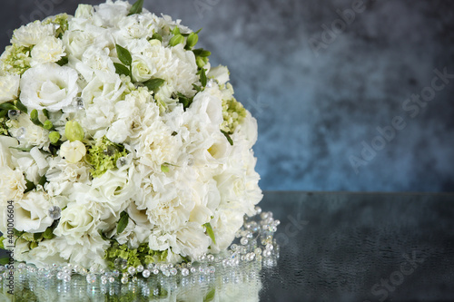 Wedding bouquet with white roses under the water drops on the mirror against grey and blue background. . 