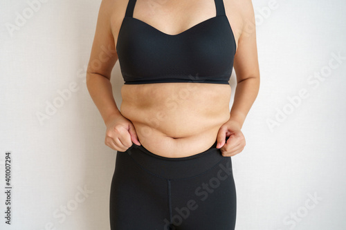 Women body fat belly. Obese woman hand holding excessive belly fat. diet lifestyle concept to reduce belly and shape up healthy stomach muscle.