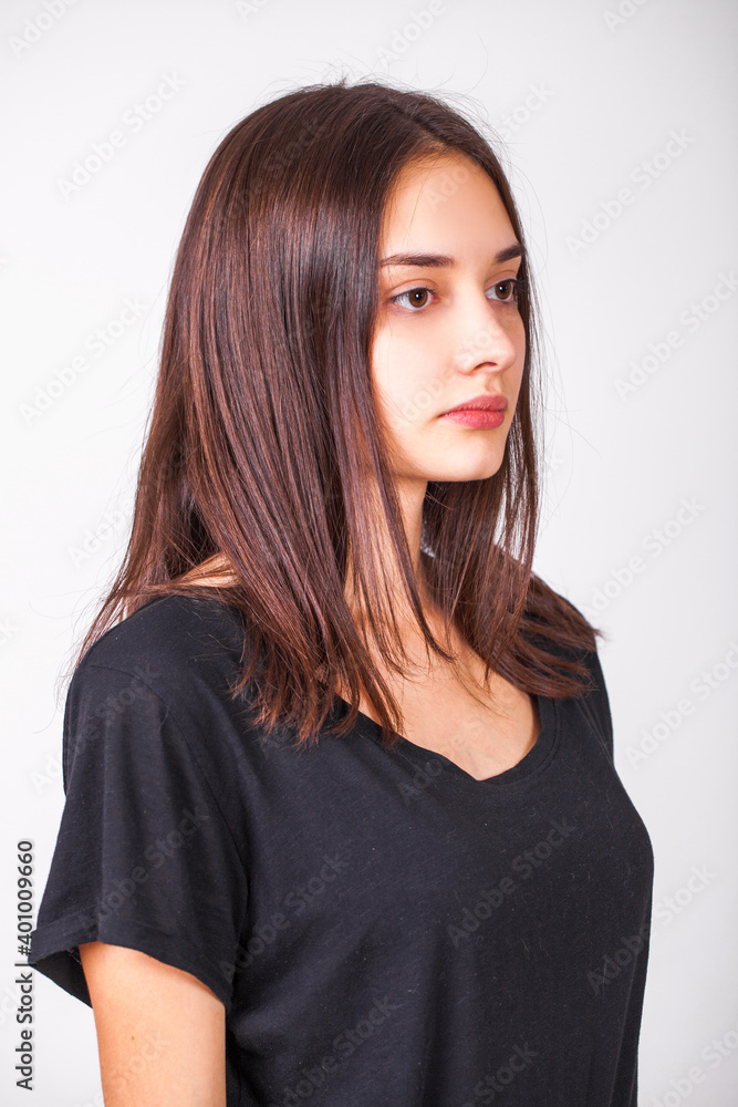 Portrait of young beautiful brunette girl in profile isolated on gray background Portrait of young beautiful brunette girl in profile isolated on gray background