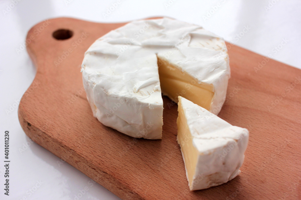 Camembert cheese on cutting board. Top view. Close up of white cheese on wooden background