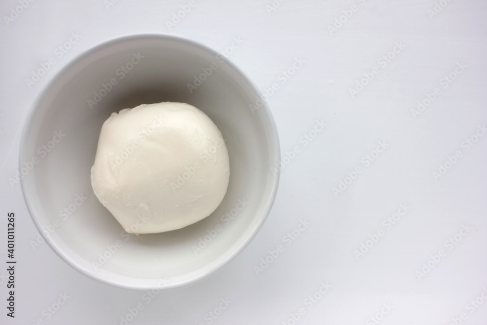 White mozzarella cheese in a bowl on white table. Overhead view. Copy space