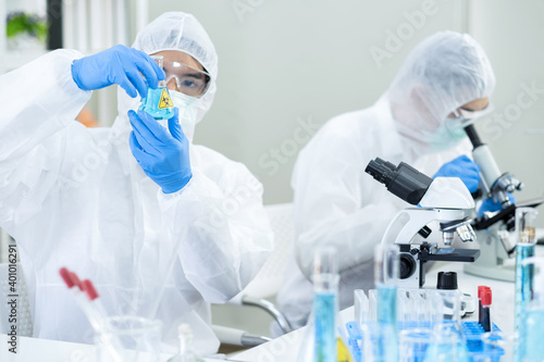 Scientists or doctor wearing personal protective and safety glass in the laboratory. Looking at the blue sample. Research on the coronavirus vaccine to prevent COVID-19. Biohazzard concept photo