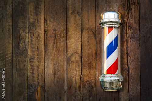 Barber pole. Barbershop pole on a wooden background with copy space. photo