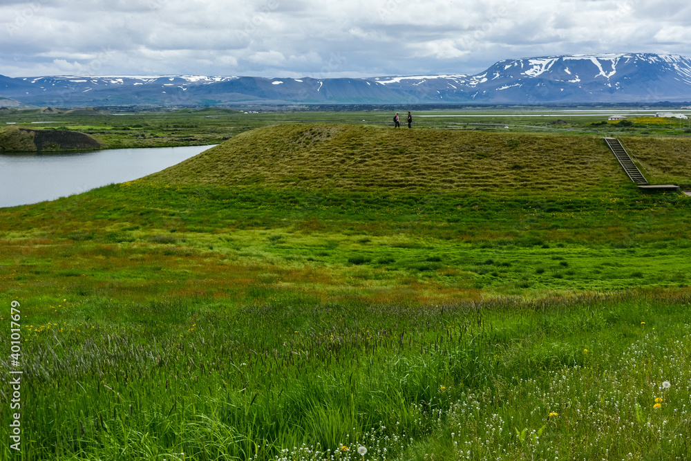Obraz premium Unrecognisable people on the coastline around the pond Stakholstjorn with pseudo craters - natural monument near Lake Myvatn in Northern Iceland in summer