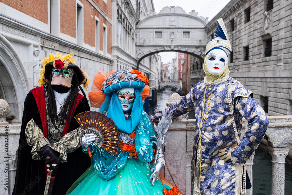 Venice, Italy - February 17, 2020: An unidentified group of people in a carnival costume in front of Ponte dei Sospiri, attends at the Carnival of Venice.