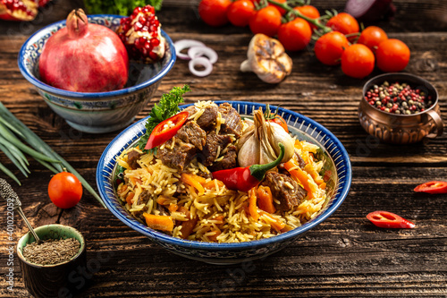 Traditional uzbek meal called pilaf. Rice with meat, carrot and onion in plate with oriental ornament, Uzbek oriental cuisine. banner format. space for text