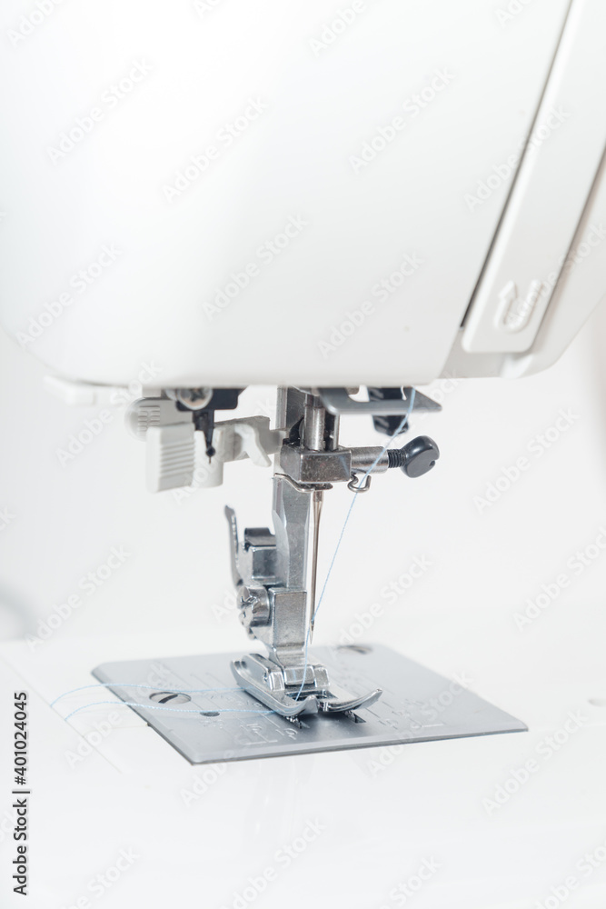 Vertical closeup of sewing machine needle against white background