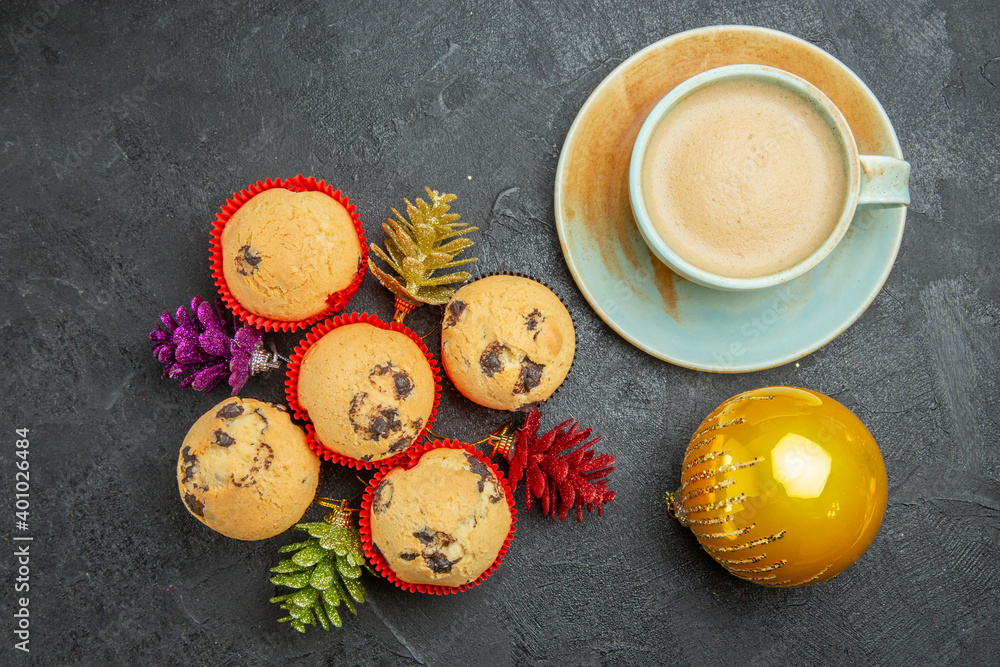 Above view of freshly baked delicious cupcakes with a cup of coffee and colorful decorations on dark background Above view of freshly baked delicious cupcakes with a cup of coffee and colorful decorations on dark background