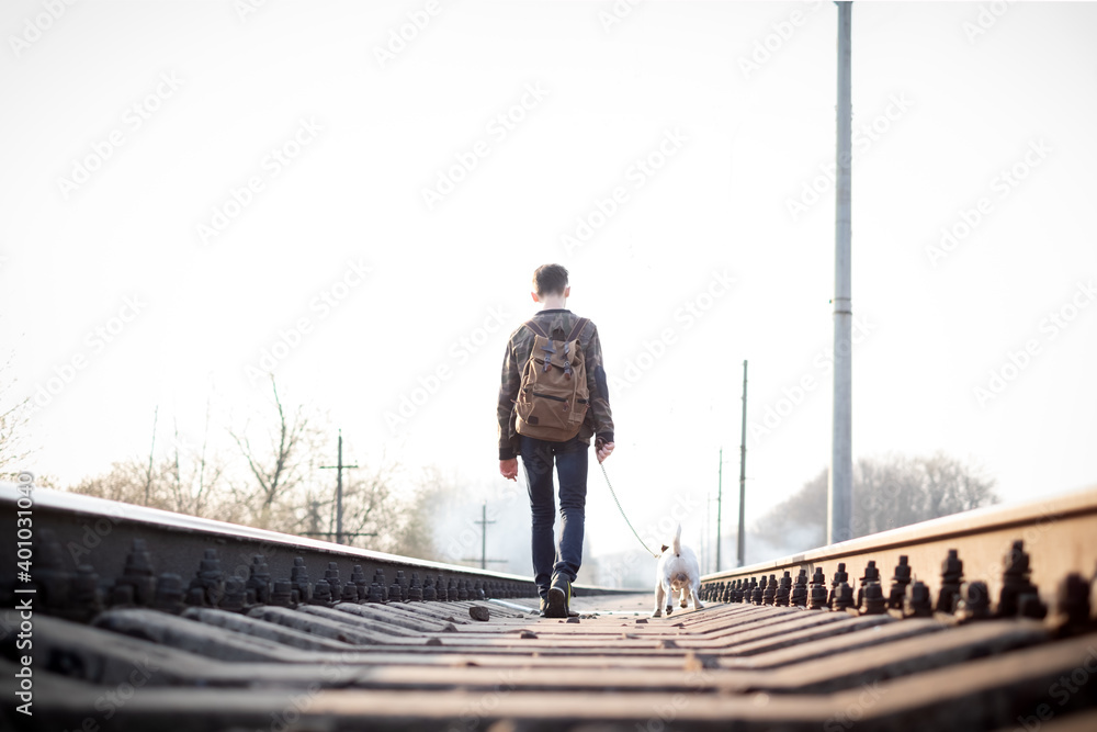 Teenager on railway walking with small white dog. Freedom and loneliness concept