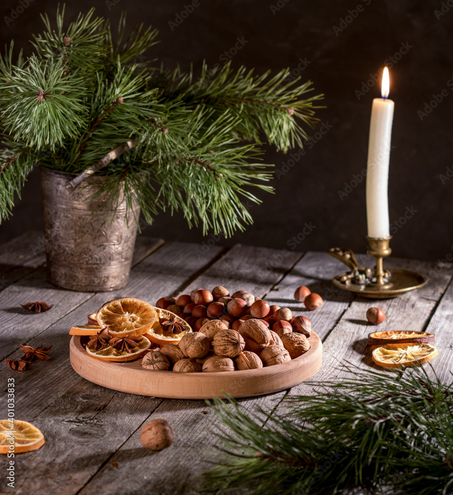 Christmas. Christmas tree, candle, walnuts, hazelnuts and dried oranges on a platter. Christmas. Christmas tree, candle, walnuts, hazelnuts and dried oranges on a platter.