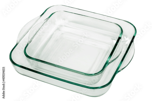 Pair of congruent superimposed rounded square Glass Baking Pans with curved handles, with smaller one placed in the bigger Casserole, isolated on white background.