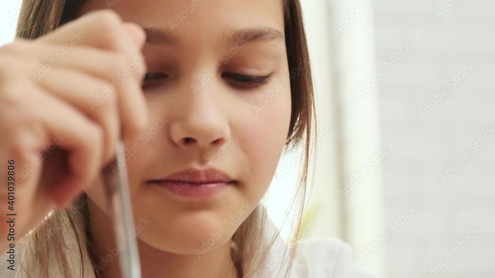 Optimistic concentrated girl child having a breakfast indoors at home while watching videos by mobile phone Optimistic concentrated girl child having a breakfast indoors at home while watching videos by mobile phone