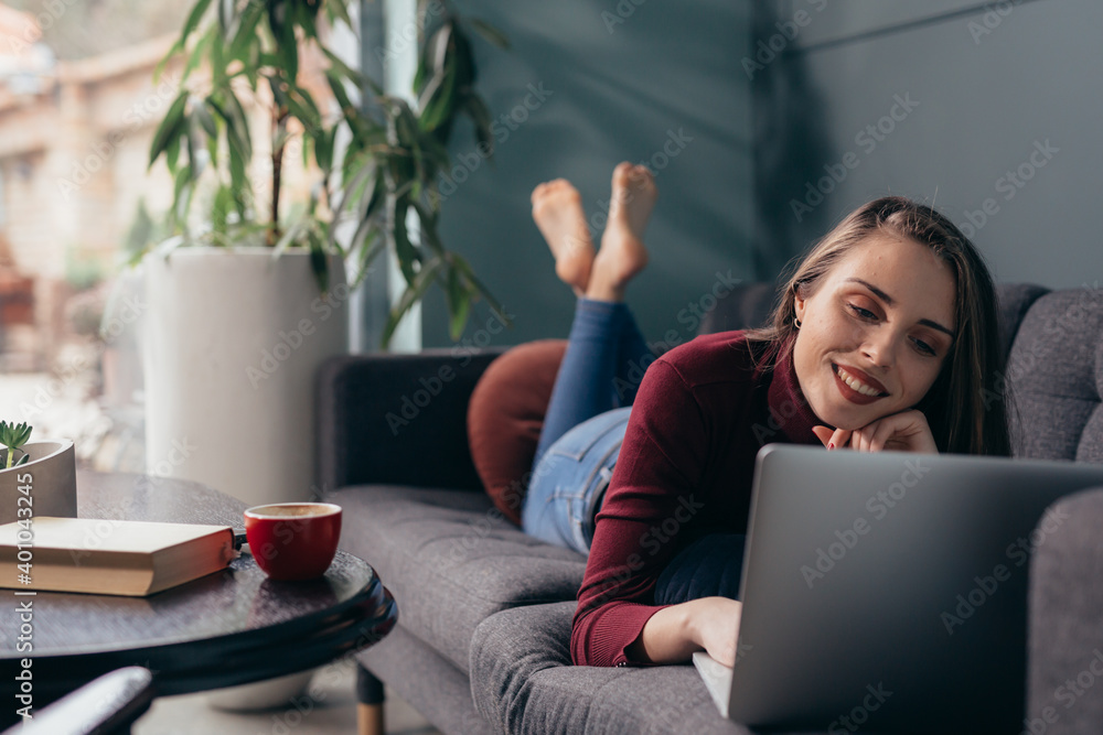 Naklejka premium woman enjoying time working on laptop computer at her home