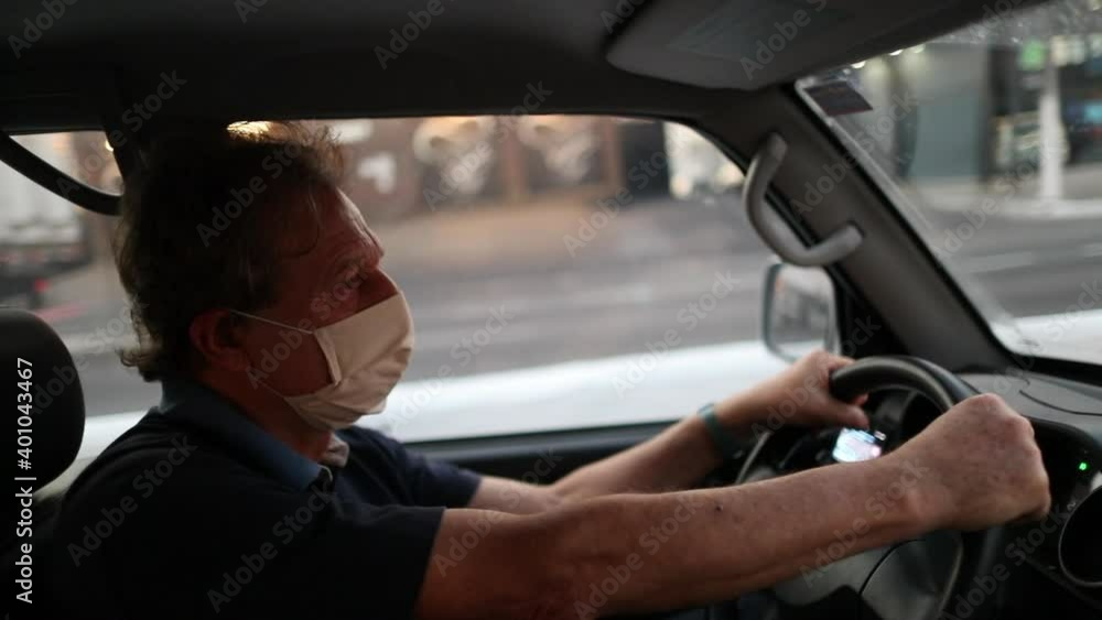 Older man looking at rear view mirror while driving and wearing covid-19 face mask Older man looking at rear view mirror while driving and wearing covid-19 face mask