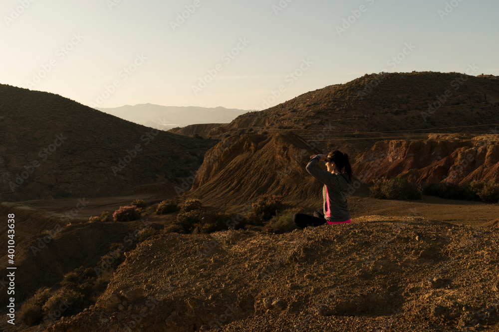 Woman siting with her hands on her eyes with mountains background