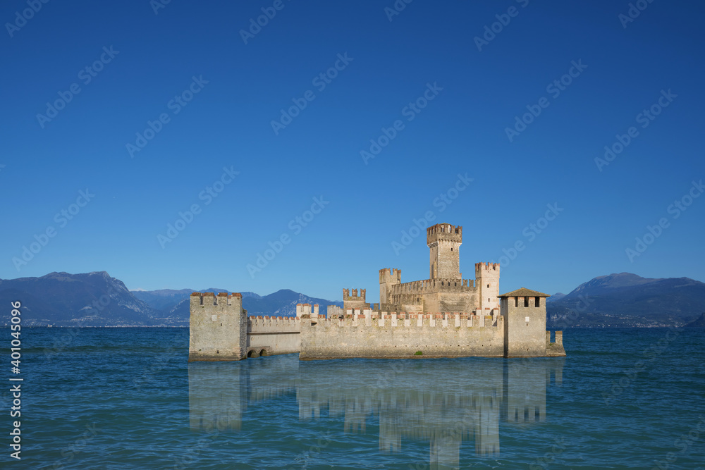 Medieval historical castle on the water. High mountains along the coastline.