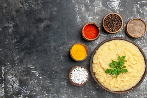 top view mashed potatoes in wooden bowl sea salt black pepper red pepper turmeric in small bowls on dark background with copy space