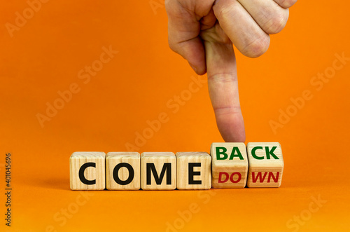 Comedown or comeback symbol. Male hand flips wooden cubes and changes the word 'comedown' to 'comeback'. Beautiful orange background, copy space. Business and comeback concept. photo