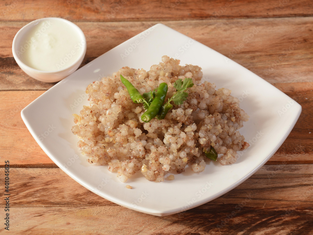 Sabudana khichdi / Khichadi is an Indian Fasting Food Recipe consume during navratri, ekadashi or ganesh chaturthi, dish isolated over a rustic wooden background, selective focus