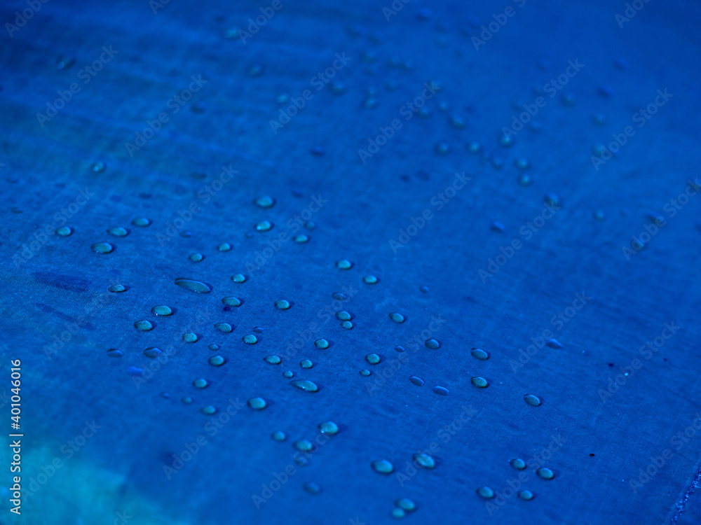 Obraz premium Water drops on waterproof membrane fabric. Detail view of texture of blue synthetic waterproof cloth. Morning dew on tent.