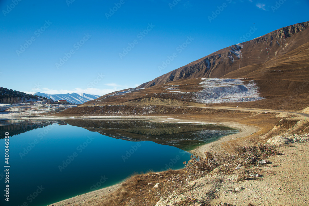 A lake high in the mountains in winter with the blue sky and reflection in the water