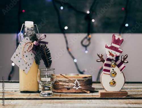 Homemade alcohol egg liquere with jar, candle and snowman decoration on wood table photo