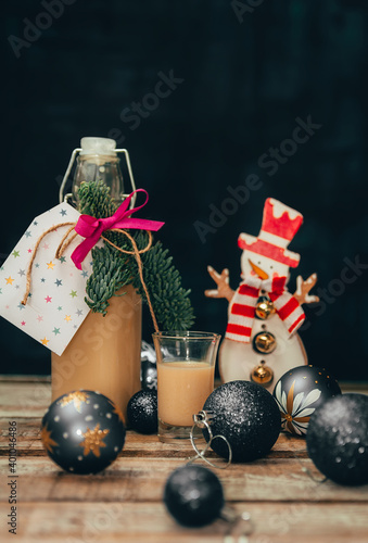 Homemade alcohol egg liquere with jar, candle, snowman and christmas ball decoration on wood table photo