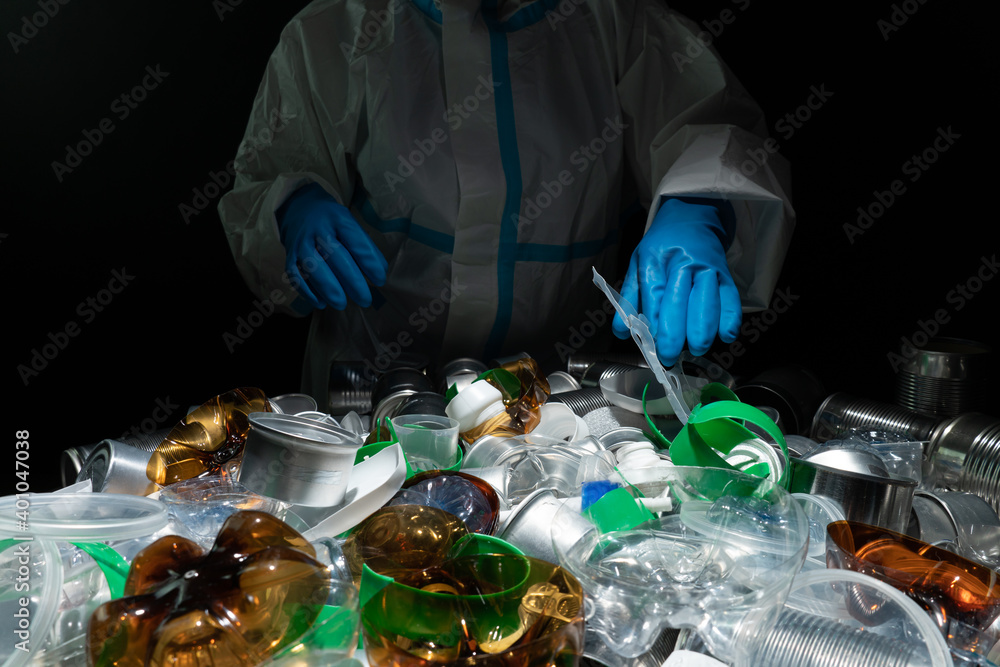 Recycle worker in gloves, sorting one time used plastic bottles and tin metal cans in the trash. Depiction of recycle plant facility. Plastic garbage overproduces and harm to environment. Recycle worker in gloves, sorting one time used plastic bottles and tin metal cans in the trash. Depiction of recycle plant facility. Plastic garbage overproduces and harm to environment.