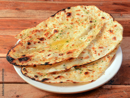 Butter naan, isolated over a rustic wooden background, selective focus photo