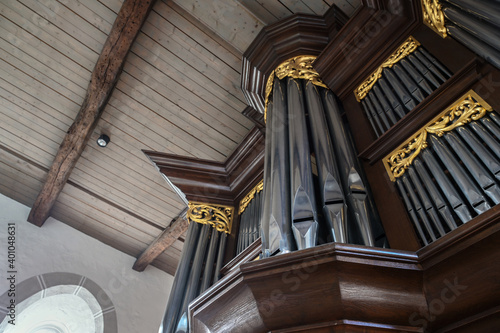 Pipe organ case facade in dark wood with golden decorations in St. Mary's Church of the village Gudow, Schleswig-Holstein, Germany, selected focus photo