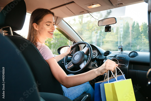 Beautiful woman with shopping bags in car