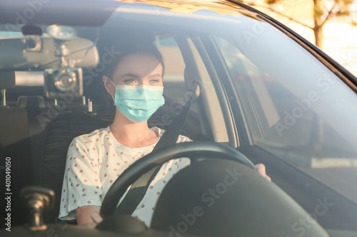 Beautiful woman wearing medical mask in modern car