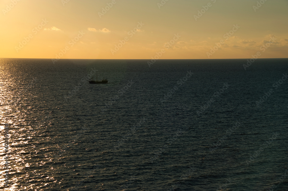 Sailing ship at sea at sunset.