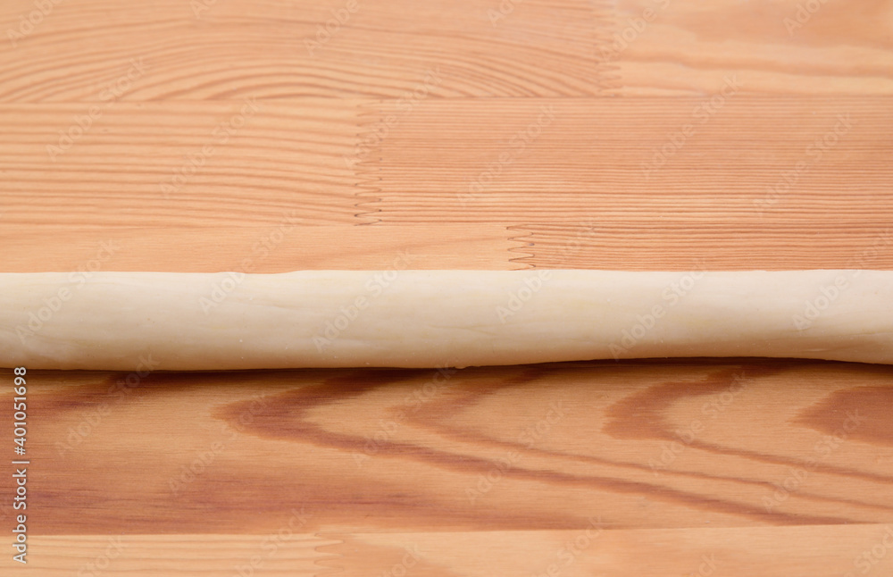 Long dough sausage on a wooden table