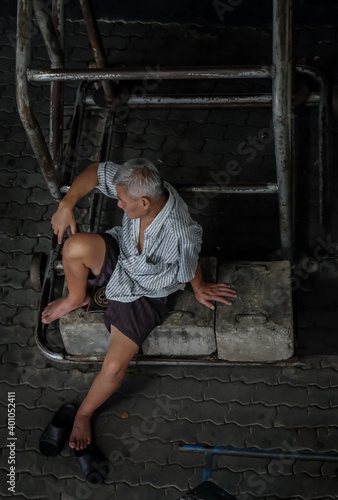 Bangkok, Thailand - July 10, 2019 : Senior man Sit and relax under basketball backboard at community stadium. No focus, specifically.